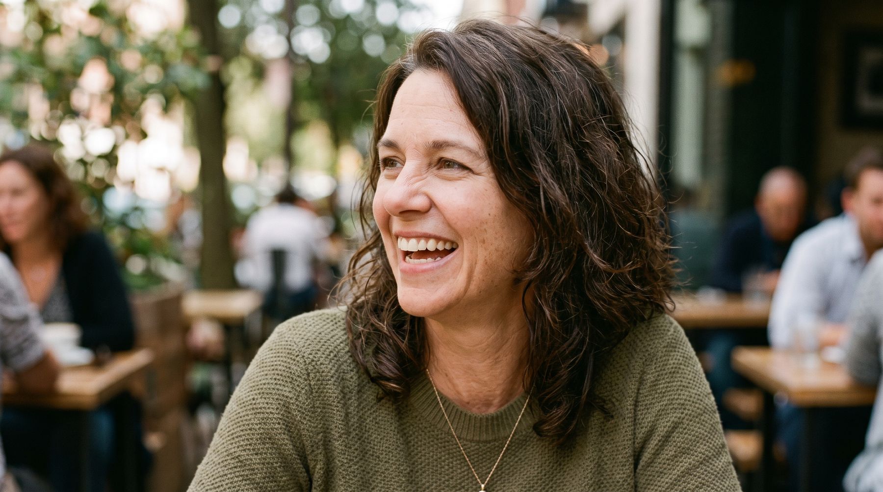 A woman laughing, relaxed, sitting in a busy café